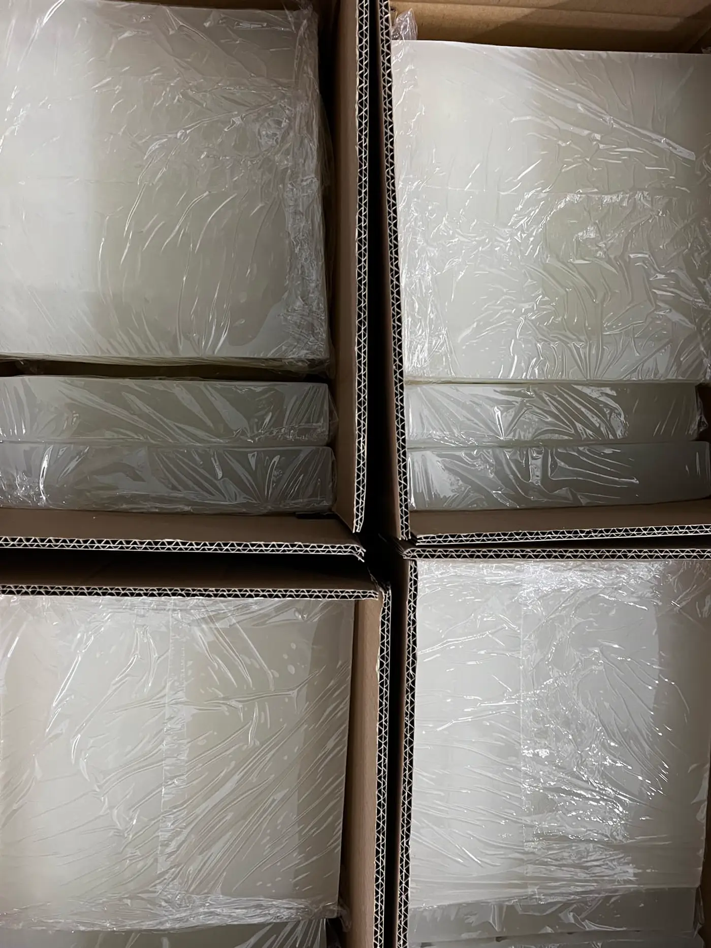 Stacked white silicone trays wrapped in plastic inside cardboard cartons